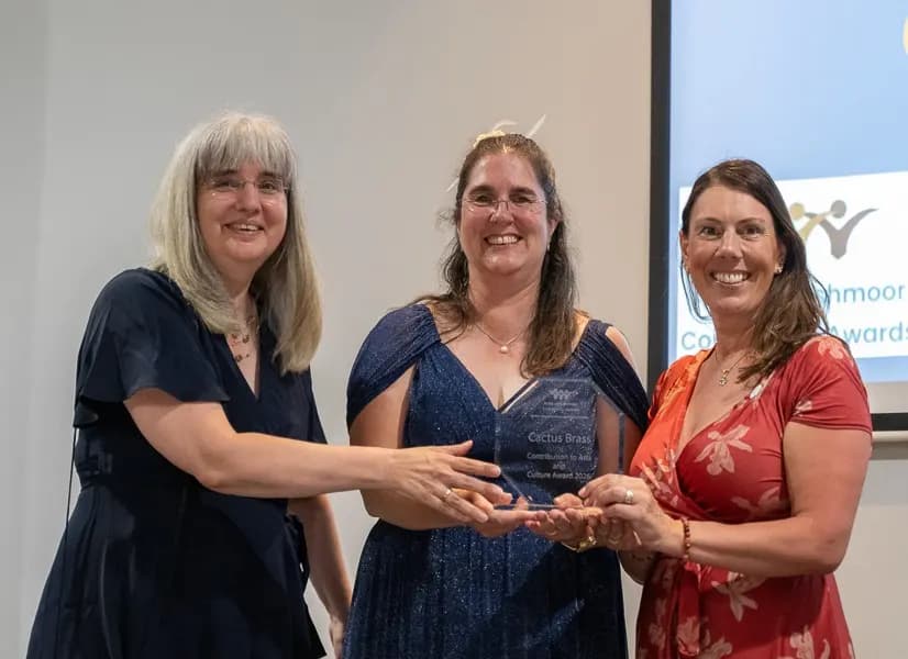 Three women holding a glass trophy together at the Pride of Rushmoor Community Awards 2026